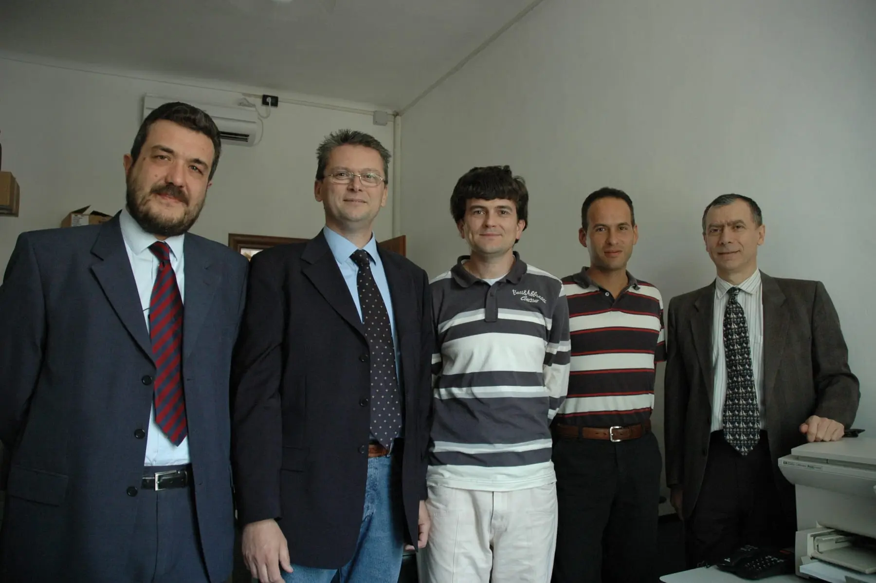 Cinque persone in piedi in un ufficio, nei primi anni novanta
